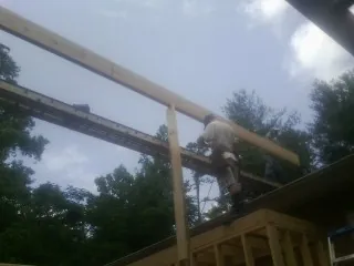 Carpenter setting a ridge beam over a new addition frame — Ice Dam Removal by Roofing Brothers in Juda