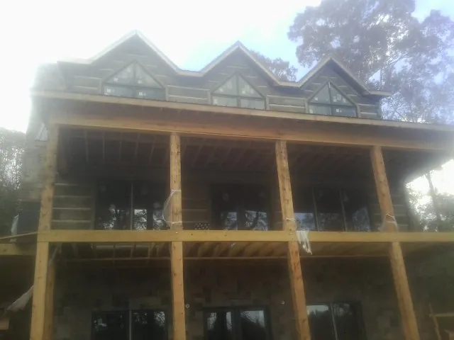 Dormers and porch framing on a large log home under construction — Roof Coating work by our crew in Juda