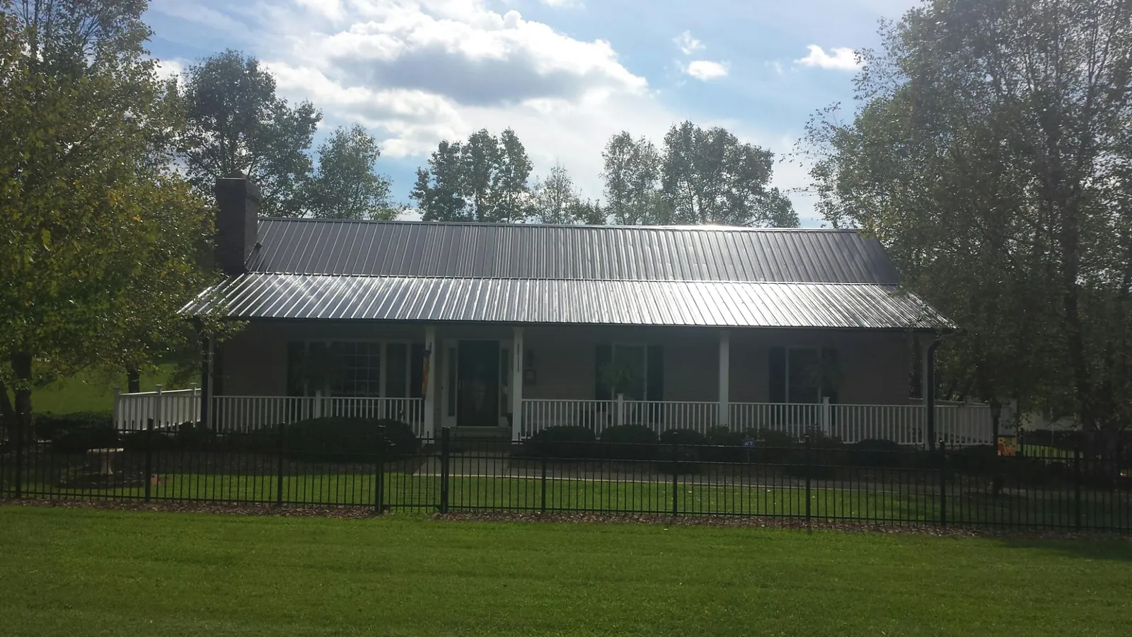 Gray metal roof on a brick ranch with a full width front porch — Gutter Guard Installation work by our crew in Juda