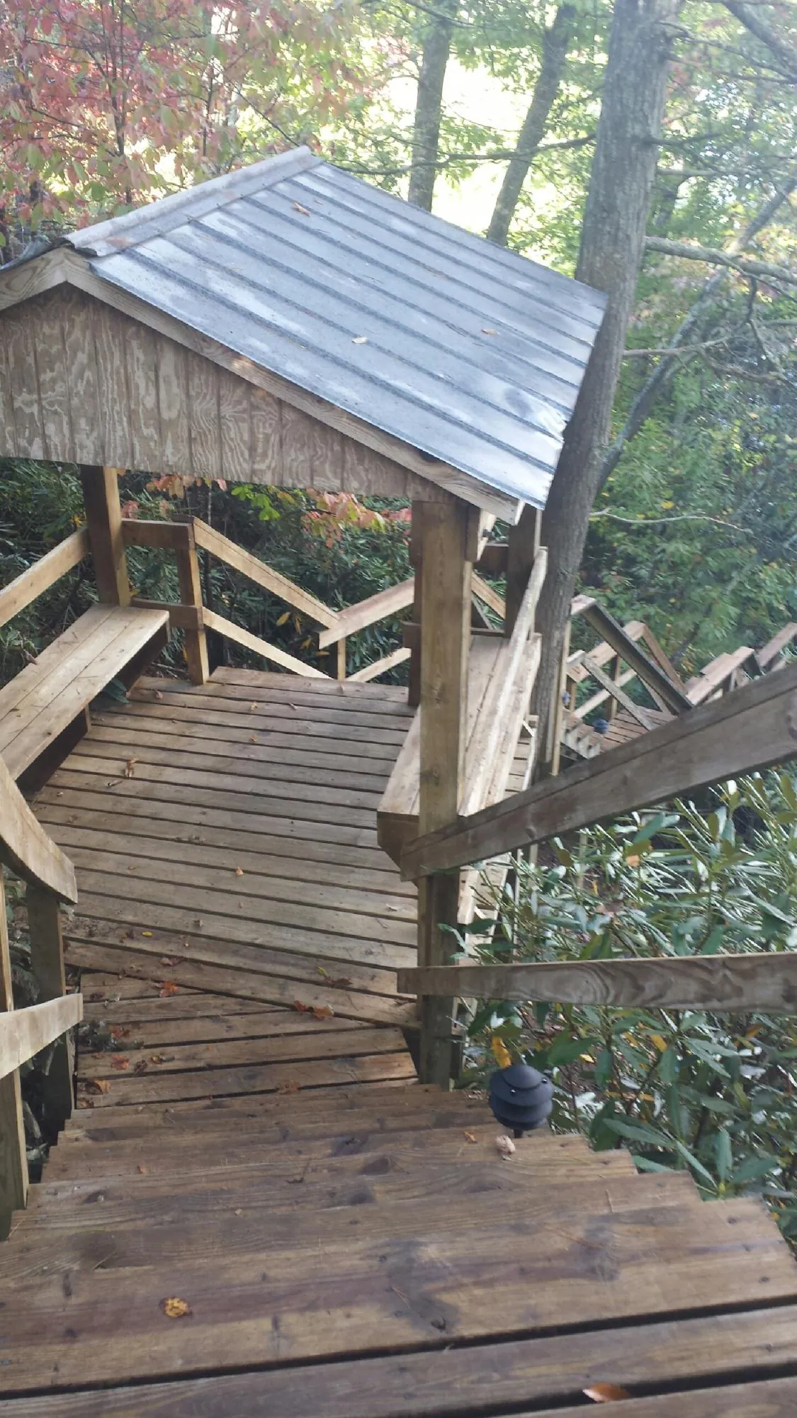 Metal roofed shelter over wooden steps on a wooded walkway — Skylight Repair & Installation work by our crew in Juda
