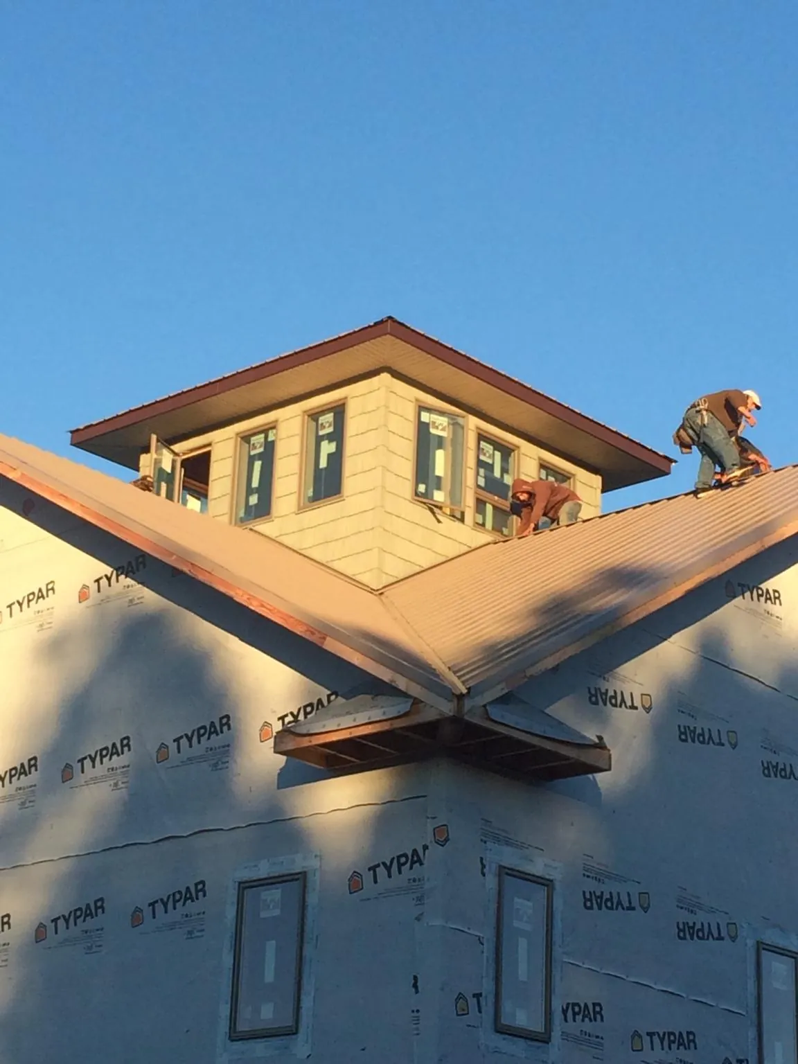 Roofers working around a rooftop cupola on a new metal roof at sunset — Roof Waterproofing in Juda by Roofing Brothers
